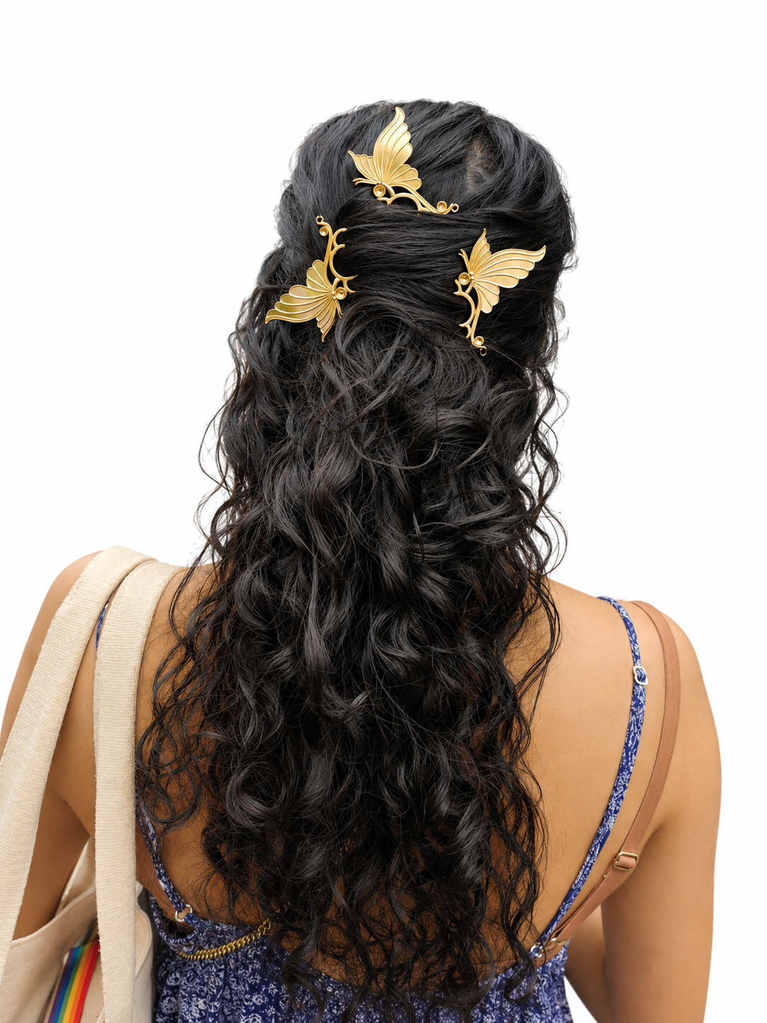 Woman with long, wavy black hair adorned with gold hair accessories on a white background