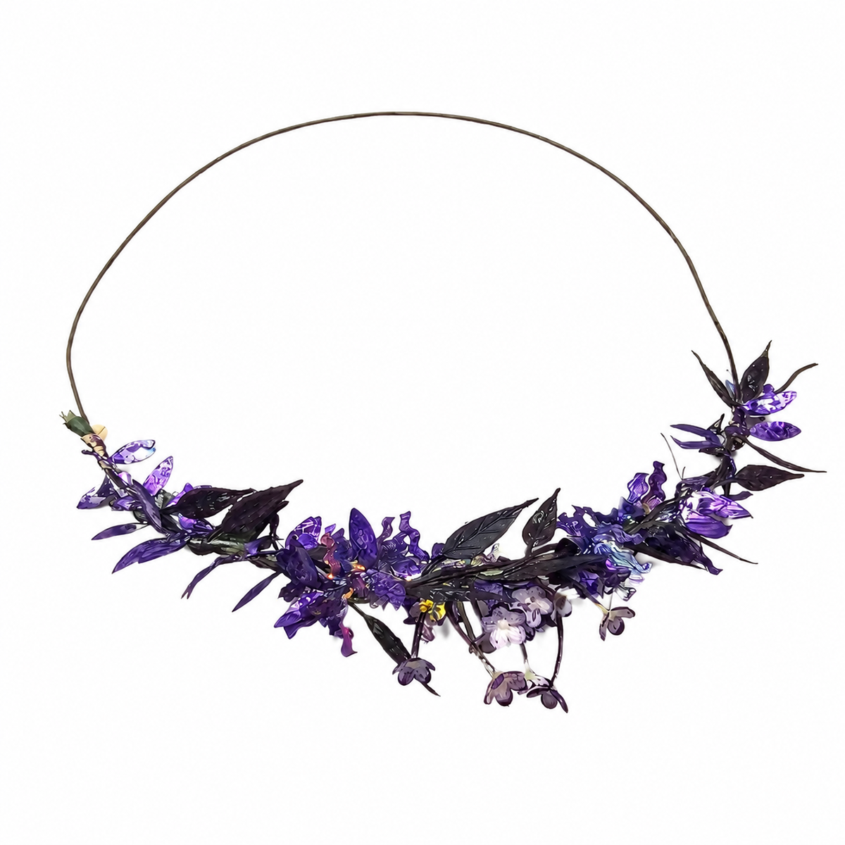 A floral crown necklace featuring purple and violet artificial flowers with dark green leaves on a thin brown wire band, set against a plain white background.