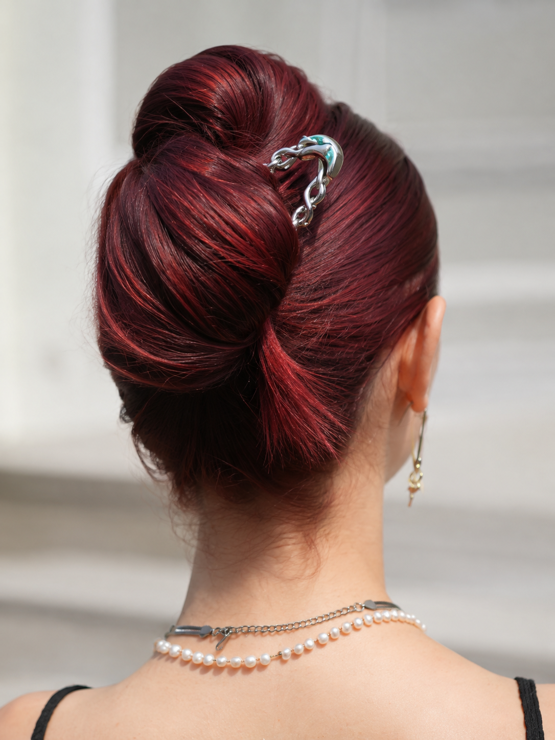 Silver chain hair pin securing a burgundy red twisted updo hairstyle